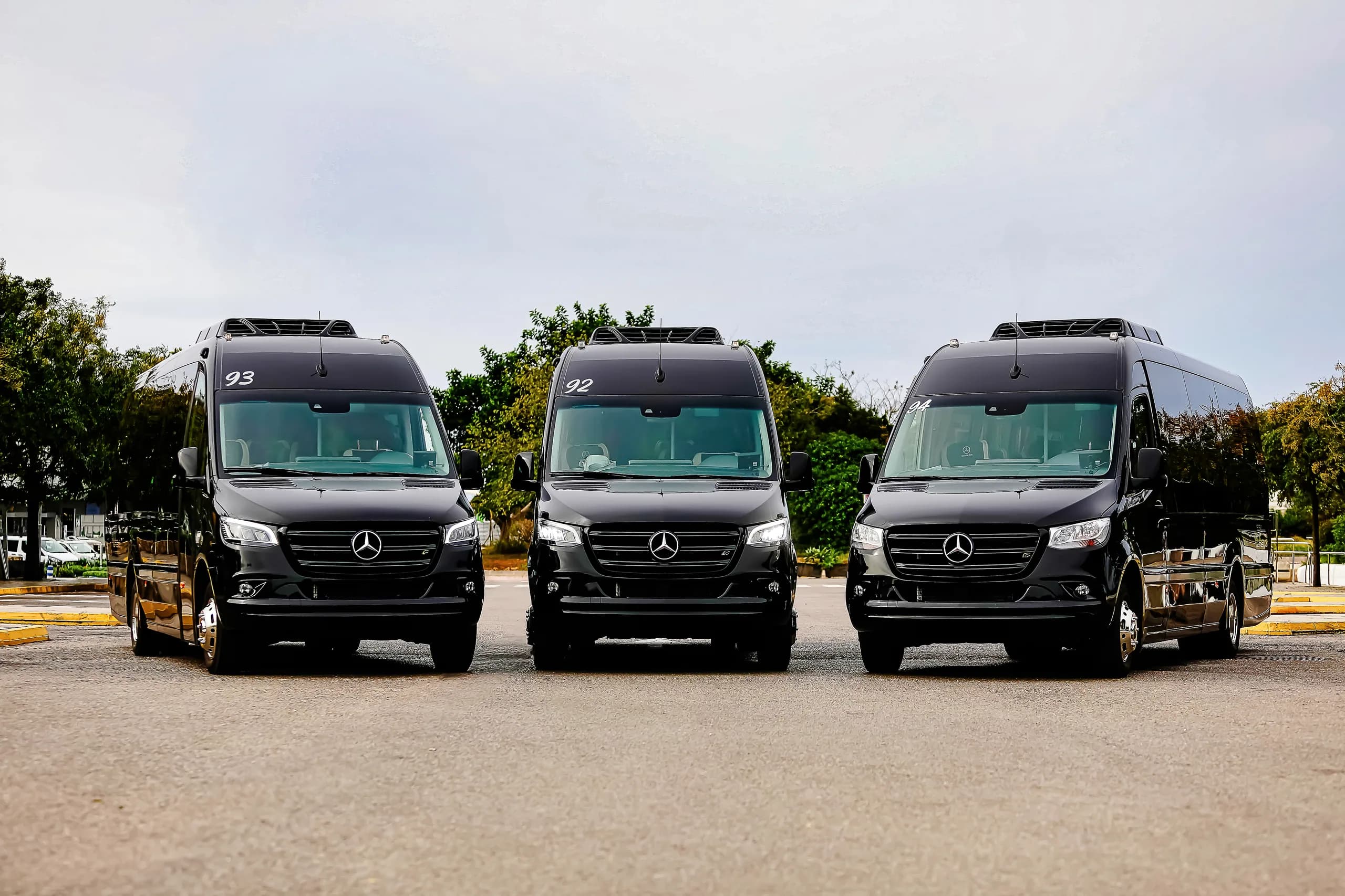 Three black Mercedes Sprinter minibuses photographed head-on, symmetrically arranged